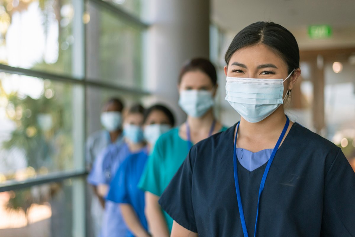 profesionales médicos parados en una fila sonriendo detrás de máscaras