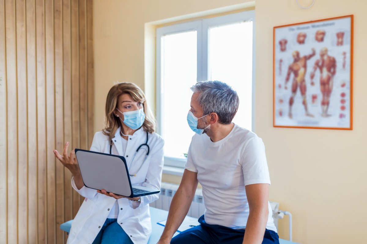 Doctor speaks to patient while wearing masks