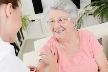 Older woman getting a shot by a health care provider